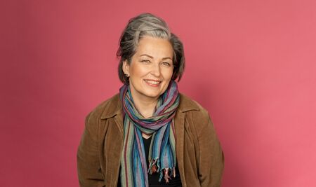 Happy gray-haired woman smiles broadly sexy posing in studio on pink background. Good-looking mature lady with nature make-up. Beauty concept. Vogue concept.の写真素材
