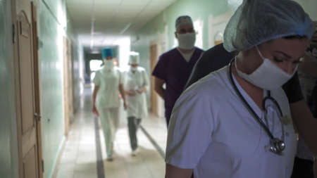 Medical team walking together along hospital corridor. Group of doctors in hurry for surgery or for...