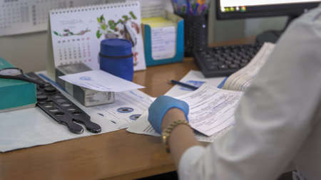 Doctor works in ophthalmologist office. Medic writes medical forms. Abstract defocused image. Focus...