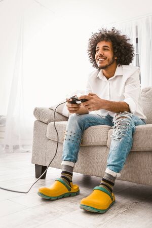 Funny man enjoys playing computer game. Young smiling gamer having fun by pressing the joystick...
