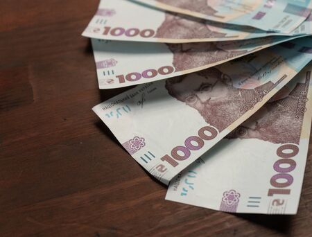 New Ukrainian paper money face value thousand hryvnia in semicircle on wooden back with empty cpace at left. Selective focus in centre of image. Close up shot.の写真素材