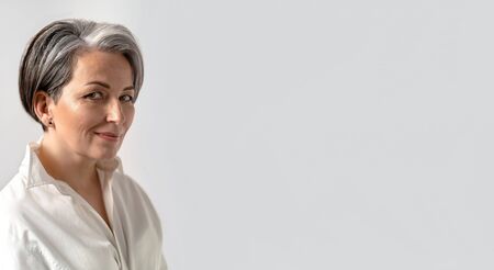 Caucasian mid adult woman smiles slightly looking at camera isolated on white background. Close up...