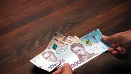 New banknotes in everyday life of Ukrainian national bank. Male hands counting new Ukrainian paper...