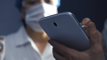 Doctor or nurse learning to use electronic tablet gadget. Selective focus on digital device in male...
