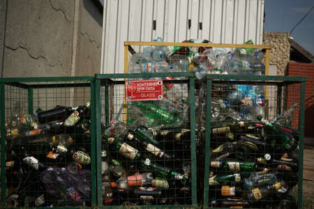 Glass bottles in container to glass garbage in foreground. Sorting and recycling garbage concept....