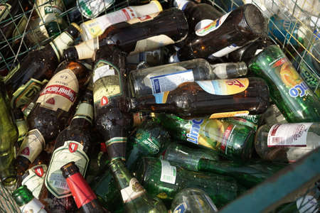 Glass bottles from beer and lemonade in a trash can. Close up shot. Sorting and recycling garbage concept. August 2018, Odessa, Ukraine.のeditorial素材