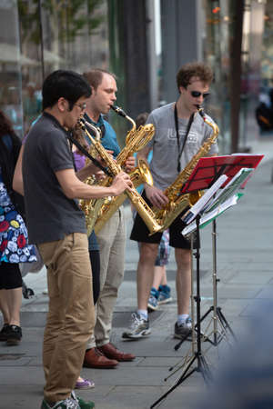 Quartet of street musicians on a city street. Four people with wind instruments, three saxophones and clarinet play in the fresh air outdoors. April, 2013. Vienna, Austria.のeditorial素材