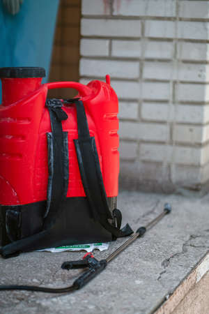 Red tank with an antiseptic for disinfection of surfaces during a coronavirus pandemic against brick...