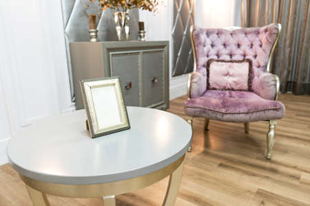 Beautiful luxury house interiour with quilted violet armchair on backfront and white round table in...