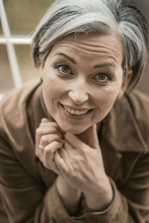 Happy mid aged woman toothy smiles looking at camera. Caucasian gray-haired model, close up...
