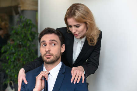 Young female boss seduces male employee. Woman stroking a mans shoulders. Abuse of work status....