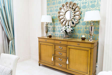 Stylish Vintage Style Home Interior with Wooden Commode and Decorated Mirror. Symmetrical Reading Lamps on Commode. Stylish Home Design.の写真素材