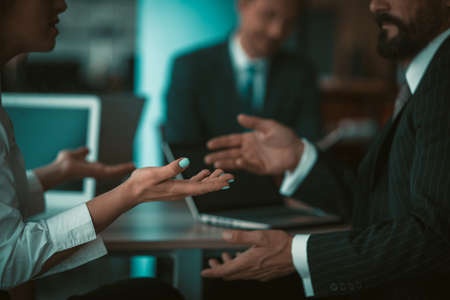 Businessman and businesswoman gesturing with hands while conversation during meeting in office. Sign language concept. Close up shot. Tinted image.