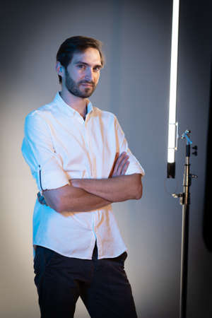 Handsome man crosed arms posing on white background among studio lighting. Presentation of Nanlite Studio LED Lighting. Backstage of presentation. June 2020, Kiev Ukraine.のeditorial素材