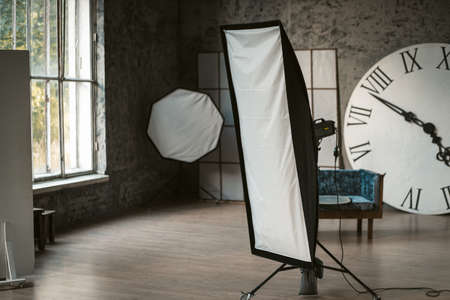 Photo studio with studio light and decorations. In the background is a huge clock with Roman numerals, there is a sofa. Studio with daylight. High quality photo.の写真素材