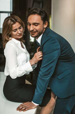 Smiling couple flirting at workplace. Intimate relationship or passionate affair in office.の写真素材