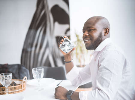 Successful Young Businessman. African American Man Smiling While Sitting At Breakfast In Luxury Apartment. Concept Of Rich Life, Personal Growth. High Quality Photoの写真素材