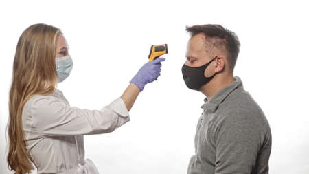 Testing patients or employees temperature using a non-contact thermometer nurse wearing a medical...