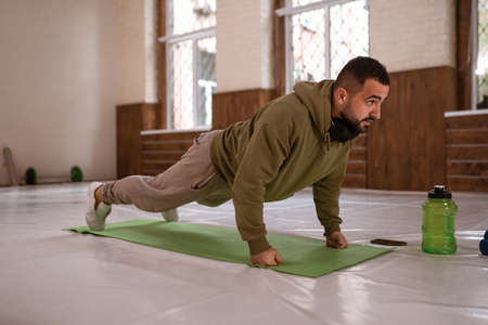 Muscular sportsman doing exercises alone in gym. Young handsome sports guy doing push ups exercise...