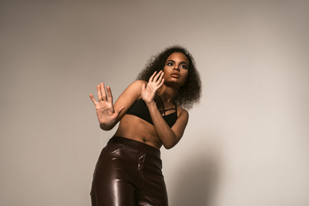 Scared with blocking hands young girl stands pinched, wearing leather pants and black top. Women violence and abused concept. trafficking Concept.の写真素材