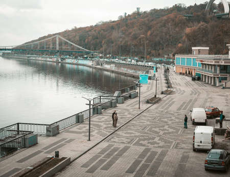 Kyiv, Ukraine, November, 2020. Capital of Ukraine, evening on the Dnipro river bank with people walking and parked cars. Kivv river station. High quality photo.のeditorial素材