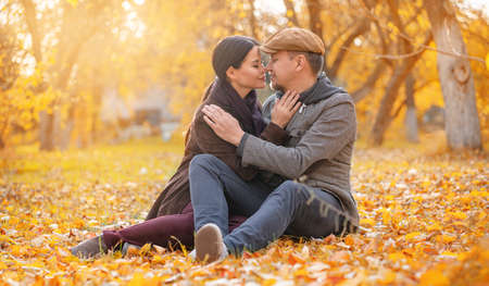 Romantic Couple Sitting on Fall Foliage Nose To Nose With Closed Eyes in Autumn Suburb. Nice Man...