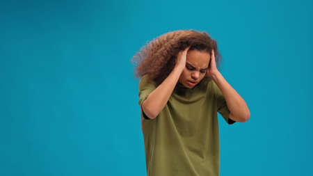 Experiencing migraine or headache African American young woman standing holding head with hands in...
