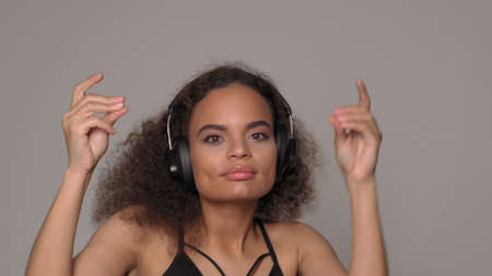 Feel the rhythm dancing listening musing in headphones young African-American girl wearing black top...