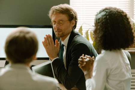 Team on meeting in modern office interior brainstorming. Colleagues discussing a new presentation sitting at coworking room looking at desktop computer.の写真素材