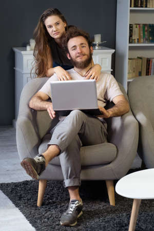 Working together young couple staying quarantined at home with sitting on the arm chairs. Happy...