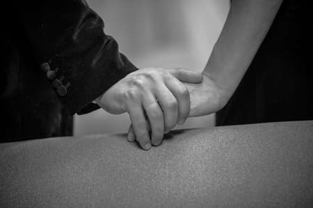 Close up on hands of beautiful young couple in home interior. Romance in relationships, love and tenderness. Husband and wife after a romantic dinner. Black and white photo.の写真素材