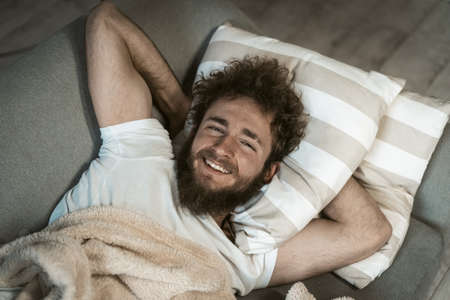Close up. Portrait of relaxed handsome curly hair man sleeping on the couch or sofa enjoying weekend...