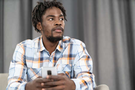 Thoughtful African American man use smartphone checking social media or updating information....