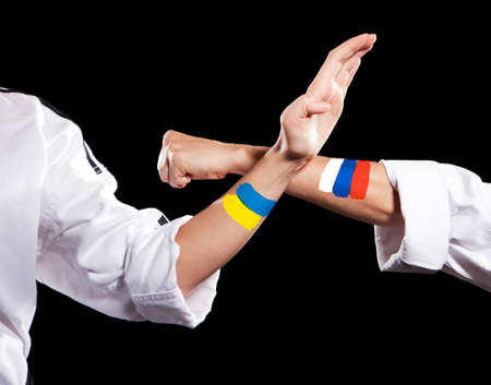 Self defense Ukraine and Russia two fighting hands of representatives of different countries. Hold hands of two fighting people isolated on black background.の写真素材