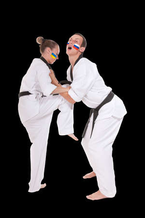Defense kick of Ukraine and Russia two fighting representatives of different countries. Woman make ankle kick to a man, two fighting people isolated on black background.の写真素材