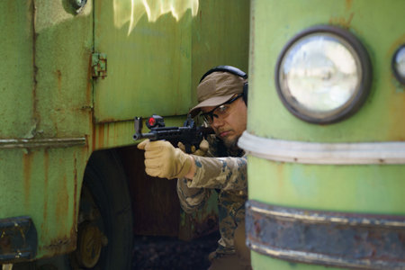 Civil disturbance training, man in tactical training course hide behind old rusty vehicles. Police man training in shooting plant with weapon. Commissioned trooper man tactical training course.の写真素材