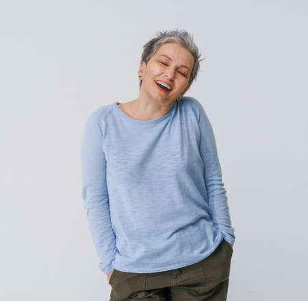 Happy smiling grey hair mature woman 50s posing shoulders slightly up and copy space on right isolated on white background. Copy space and place for product placement. Life care concept. Toned image.の写真素材