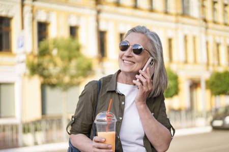 Answering phone call happy mature woman talking on the phone enjoying free time after work or...