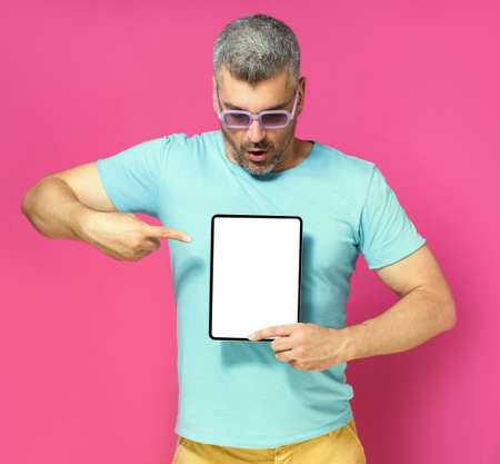 Pointing at digital tablet handsome man looking at white screen lowered his head wearing casual blue...
