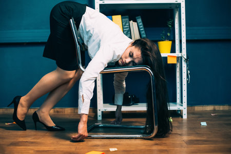 Tired businesswoman sleeping on office chair. Young exhausted pretty girl resting in unnatural pose, falling asleep on the go. Tinted image.の写真素材
