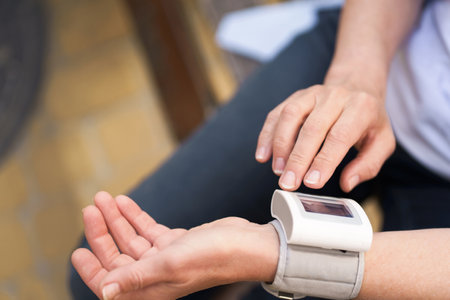 Close-up of elderly womans hands holding pressure measurement device outdoors. The image portrays the concept of health monitoring, diagnosis, and healthcare for seniors. High quality photoの写真素材