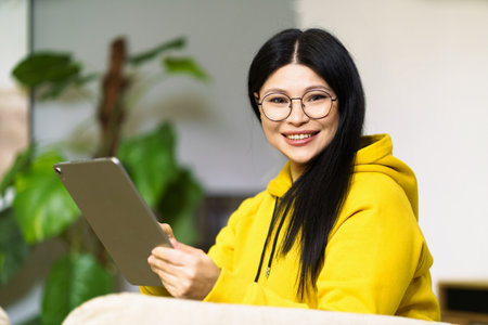 Asian girl in glasses, successfully leading her business from home, using online communication tools and modern gadgets. Concepts of entrepreneurship, innovation, and productivity, highlighting opportunities and challenges of digital future. High quality photoの写真素材