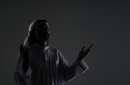 Muslim Arab man captures his spiritual devotion and faith as he prays, with hands raised to face in contemplation. Copy space for designers and publishers, black and white mid-length portrait . High quality photoの写真素材