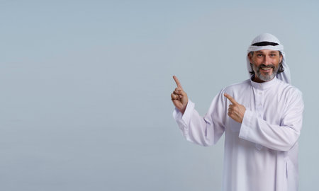 Arab man is with copy space. He is pointing his hands aside, indicating leadership, direction, and effective communication. Mid-length portrait isolated against blue background. High quality photoの写真素材
