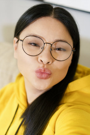 Young pretty woman takes selfies on her smartphone and applies filters and portrait processing applications. Use of technology and social media to capture and enhance self-portraits. High quality photoの写真素材