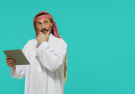 Online shopping in Middle East. Arab man holds tablet and selects goods and services. High quality photoの写真素材
