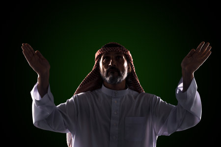 Muslim man raises his hands to sky in prayer and praise, expressing his devotion and faith in One God of Allah. Spirituality and traditional practices of Islamic culture and religion.の写真素材