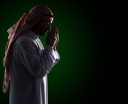 Islamic prayer ritual. Arab Man in Profile Holding Palms in Front of Face, Copy Space. High quality photoの写真素材