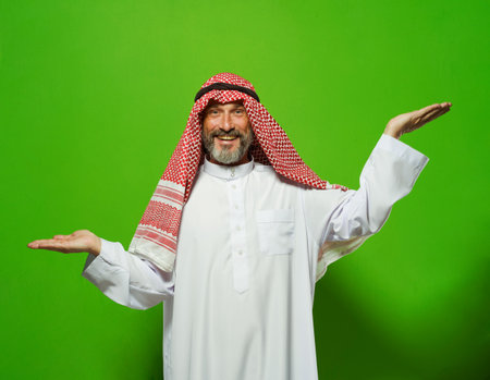 Arab mature man depicts scales with his hands at different levels. Concept of decision-making, weighing options, and finding balance. ideas of justice, equality, and fairness, using metaphor of scales to depict importance of making right choice, comparing options, and achieving balance in life. High quality photoの写真素材