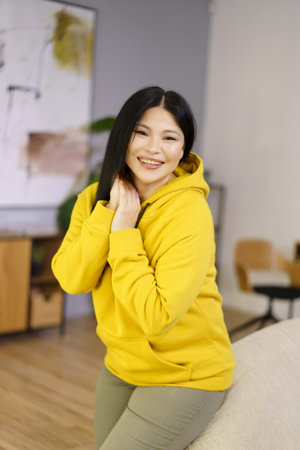 Mature Asian woman is captured in her home, enjoying the happy moments of life through the lens of lifestyle biohacking. She is surrounded by greenery and natural sunlight, as she focuses on wellness, fitness, and mental health. High quality photoの写真素材